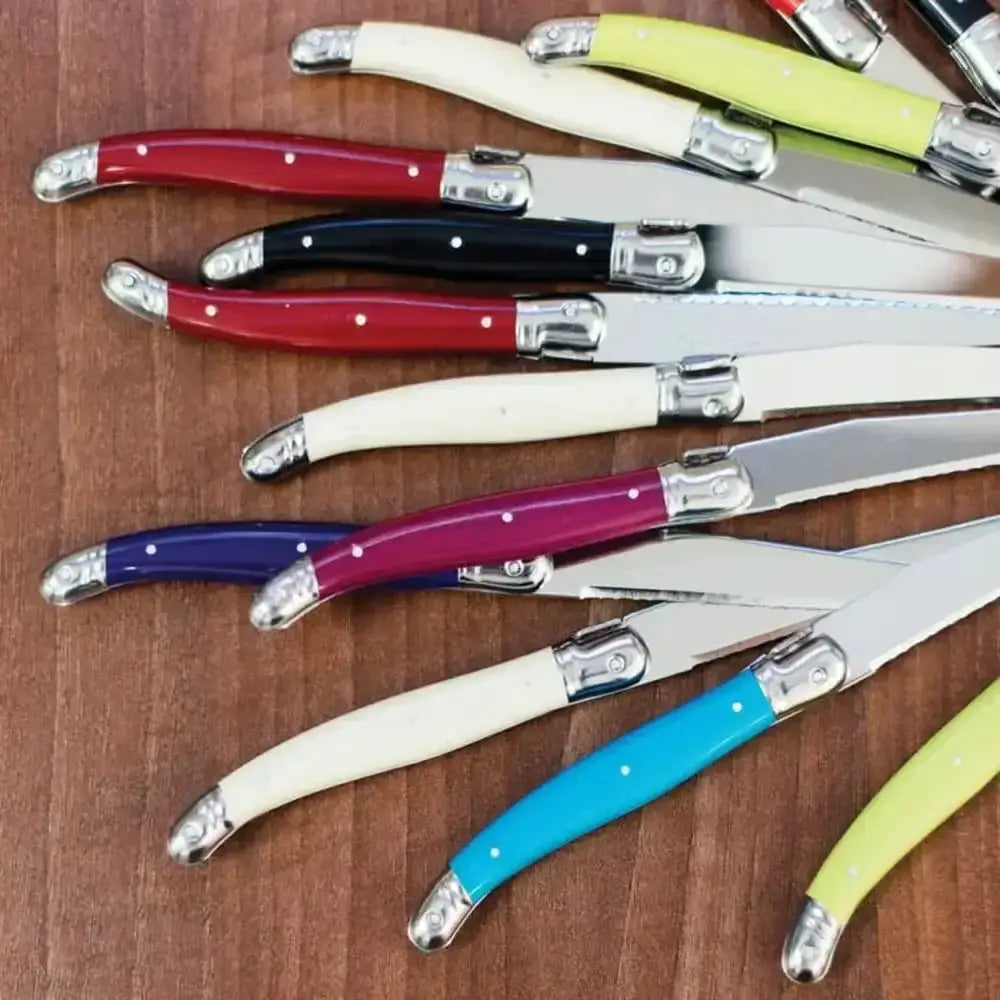 Set of colorful knives with wooden handles on a wooden surface