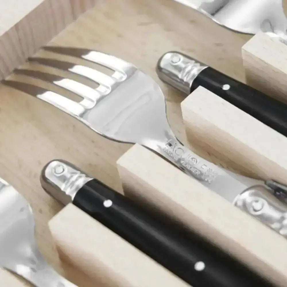 Set of silver cutlery with black handles in a wooden box