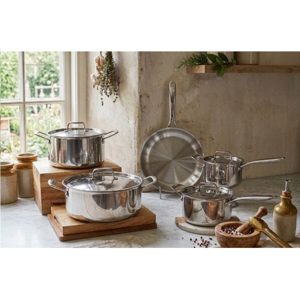 Set of stainless steel cookware on a kitchen counter with a window in the background