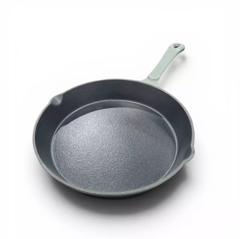 Green cast iron frying pan with a green handle on a white background