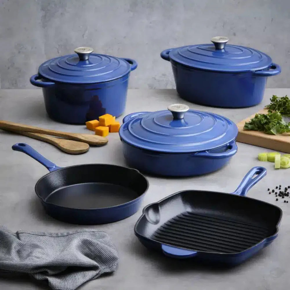 Set of blue cast iron cookware including pots and pans on a gray surface with ingredients.
