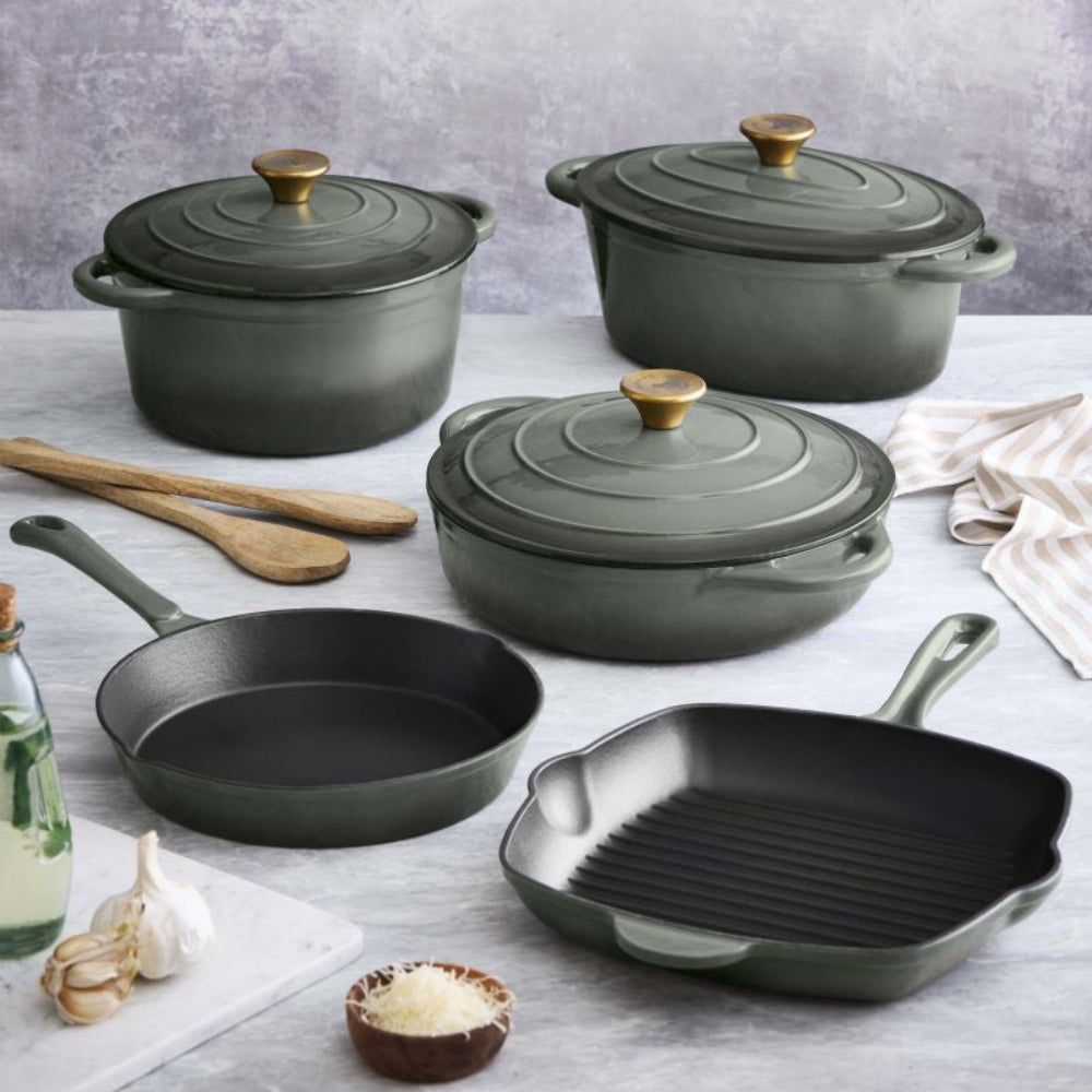 Set of green cookware including pots, pans, and a grill on a light gray surface.