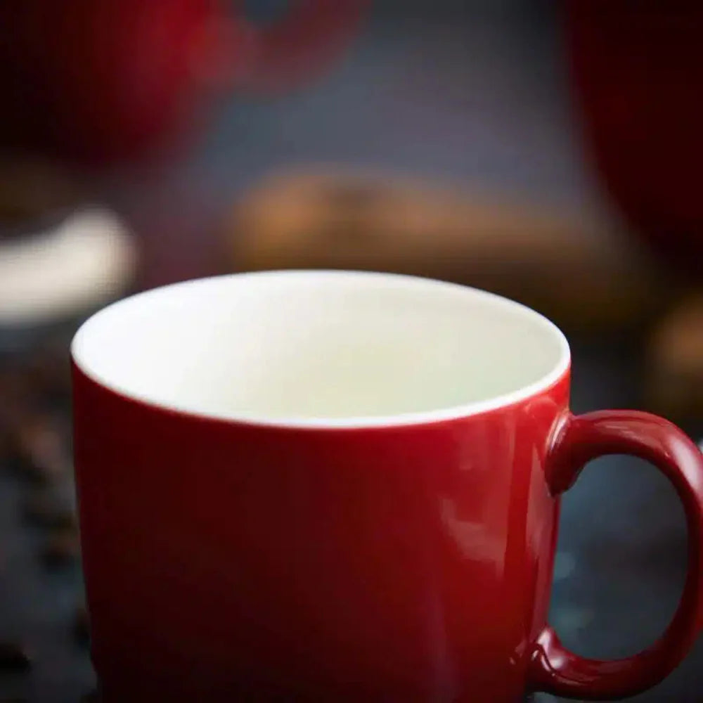 Red mug on a dark background with blurred coffee beans