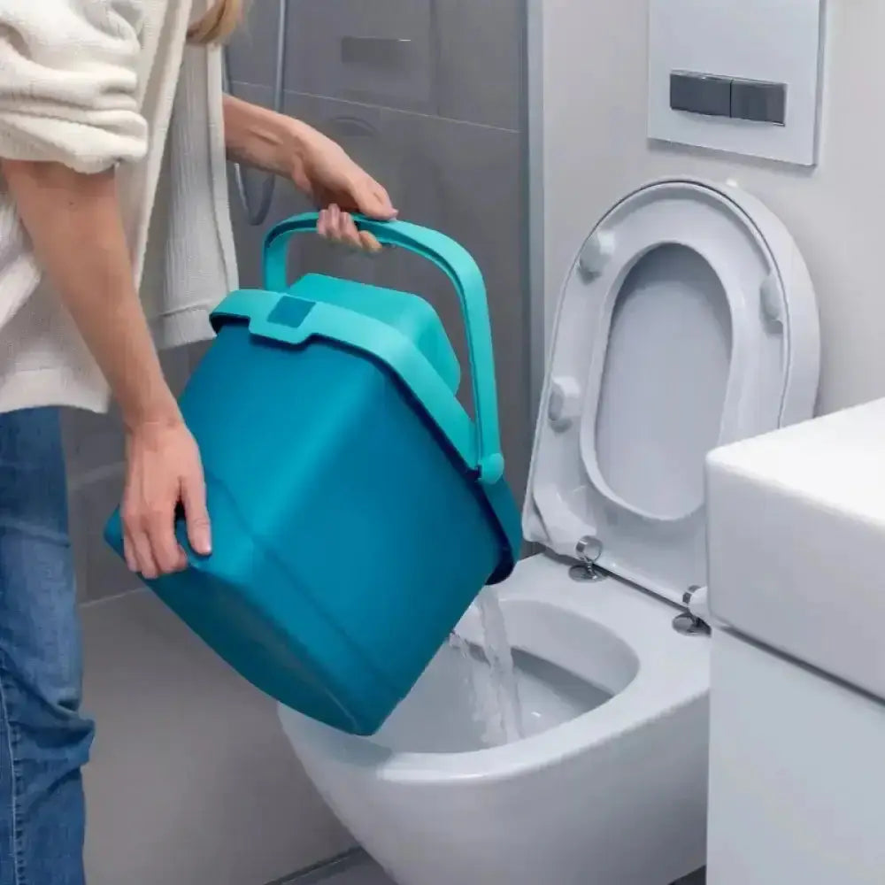 Person using a blue bucket to flush a toilet in a bathroom setting.