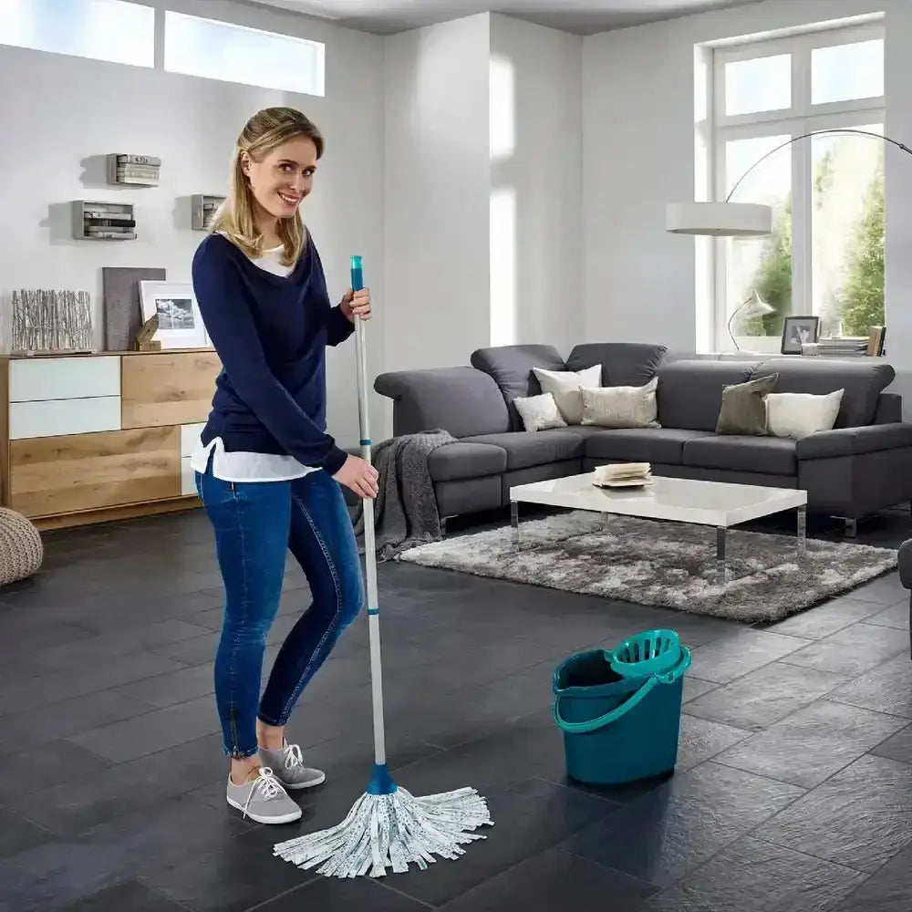 Woman cleaning a living room with a mop and bucket.