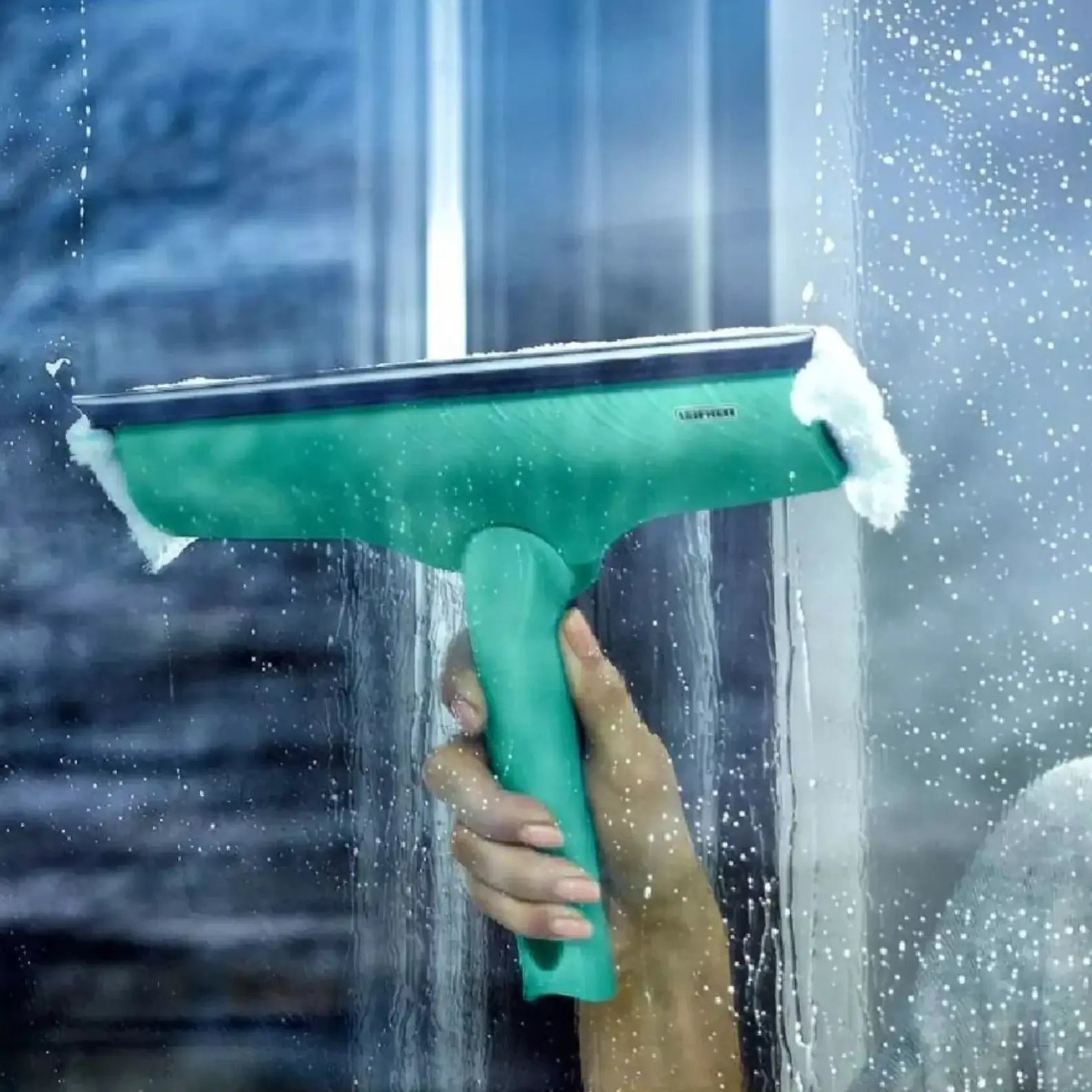 Person cleaning a window with a green squeegee