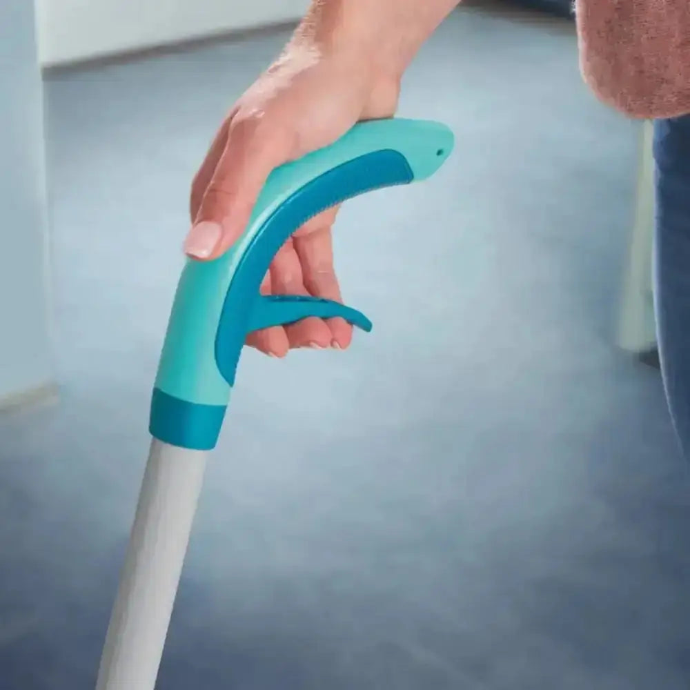 Hand holding a blue cleaning tool with a white handle against a blurred background