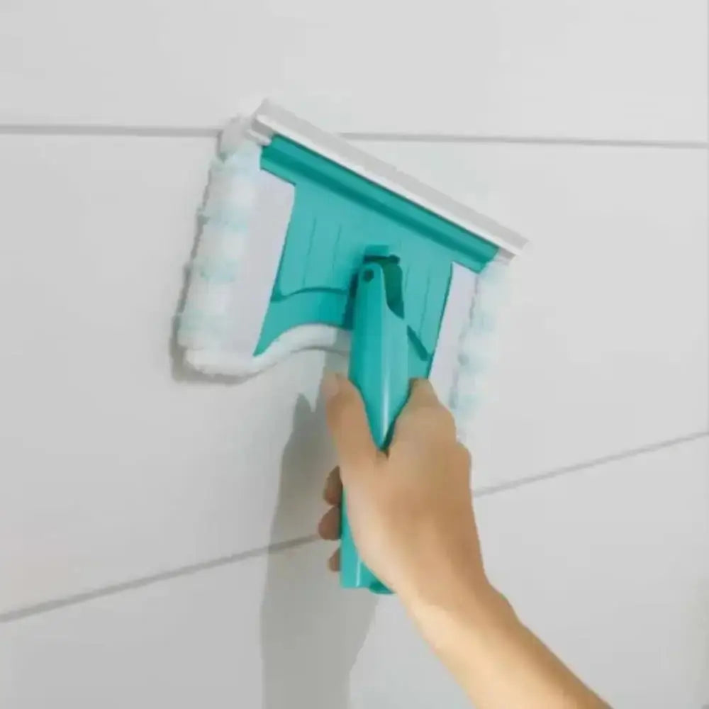 Hand using a teal tile grout cleaning tool on white tiles