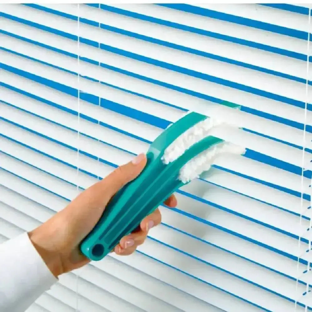 Hand using a green cleaning brush to clean white blinds