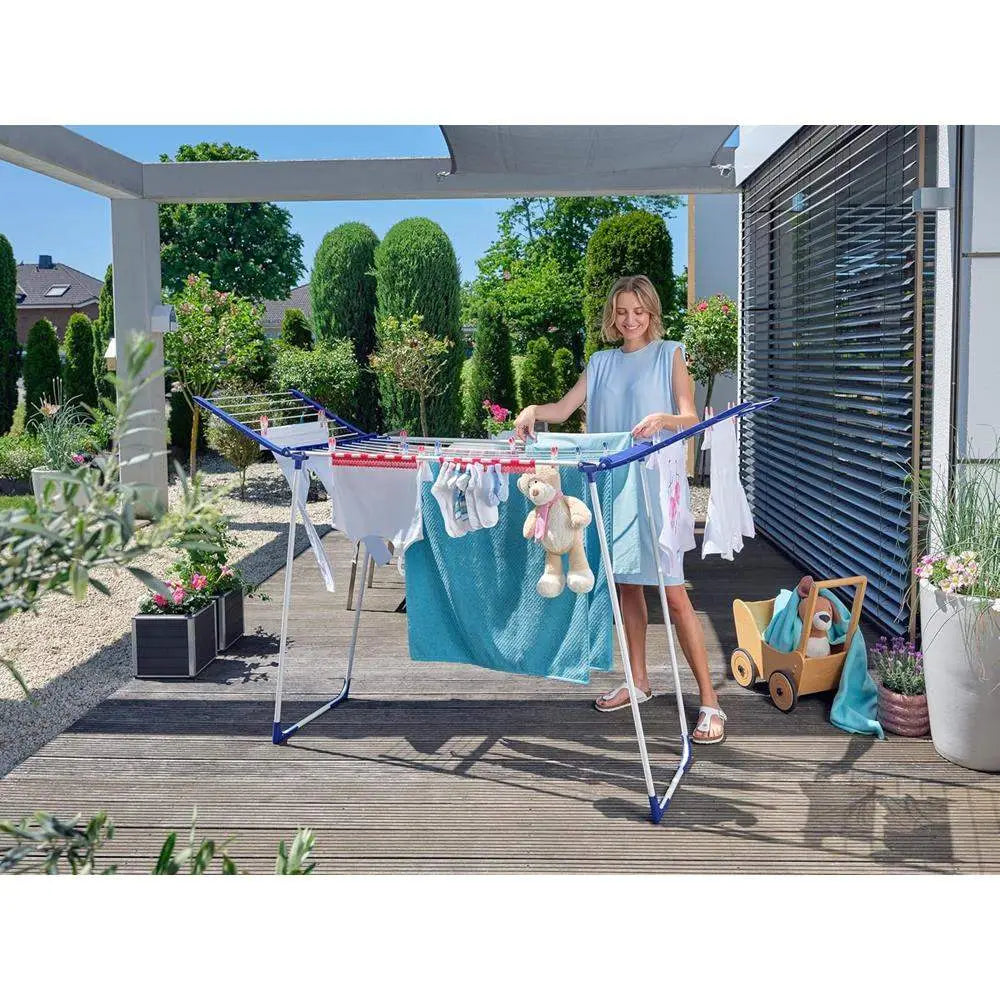 Woman hanging clothes on an outdoor drying rack with a garden background