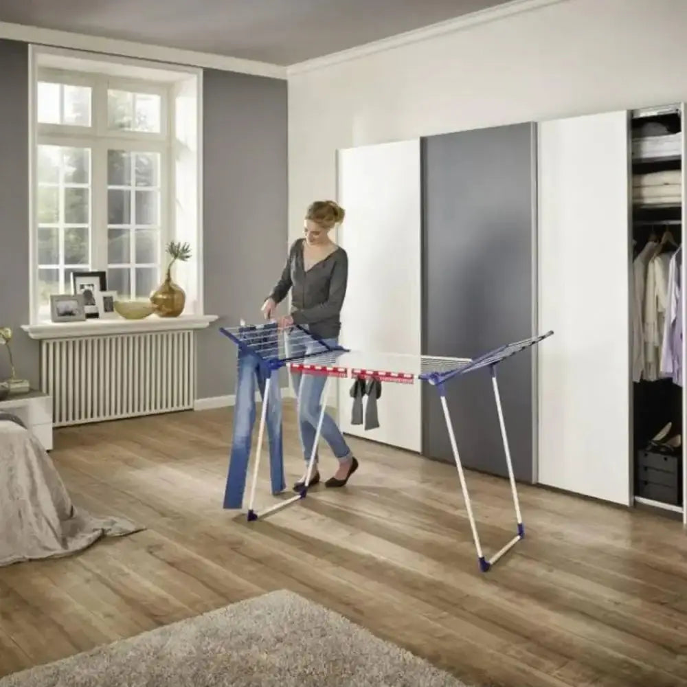 Woman using a portable dryer in a room with wooden flooring and a wardrobe.