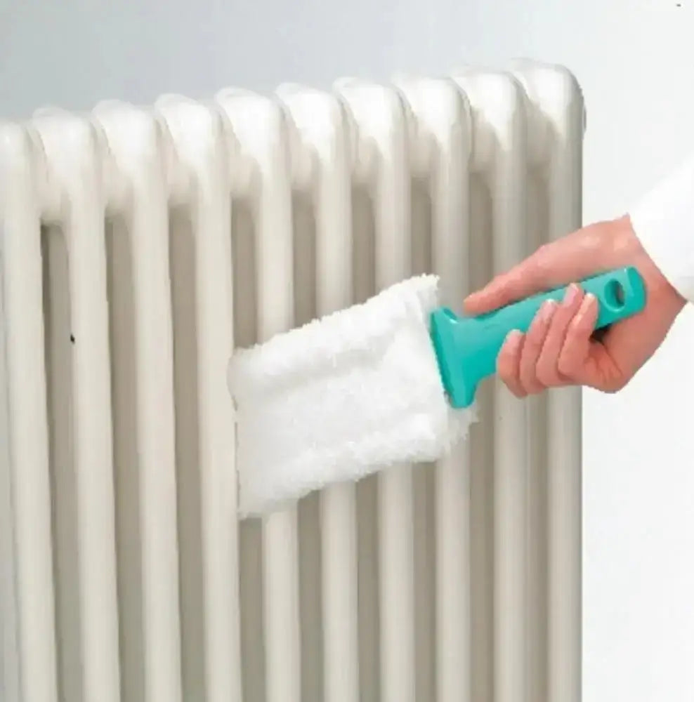 Hand using a teal radiator cleaning brush with white bristle pad on a radiator.