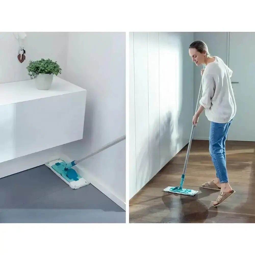Person using a mop on a wooden floor with a white wall and plant in the background.