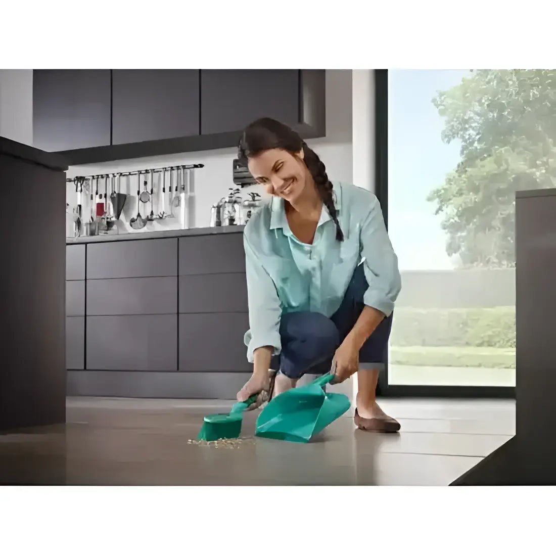 Woman cleaning a kitchen floor with a green cleaning tool