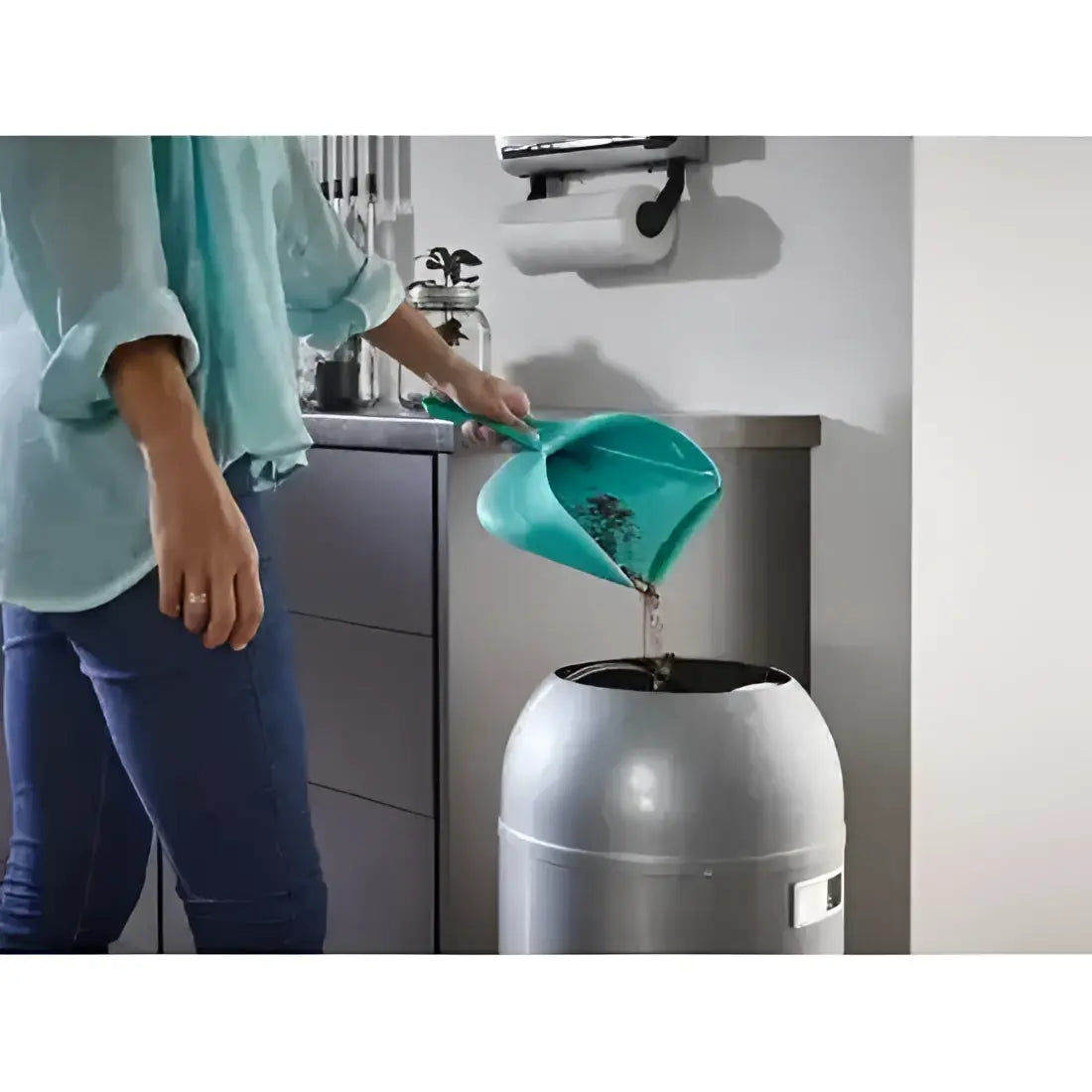 Person using a kitchen compost bin with a green scoop.