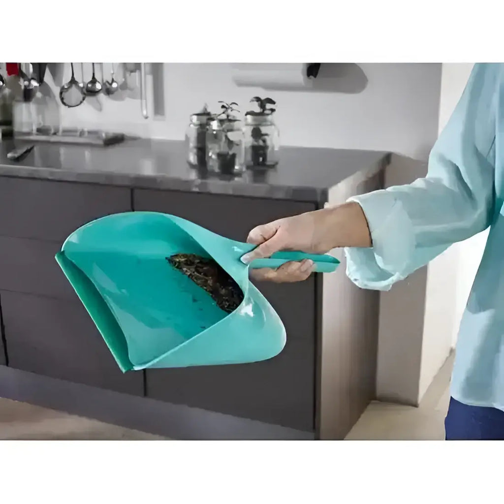 Person using a teal dustpan in a kitchen setting
