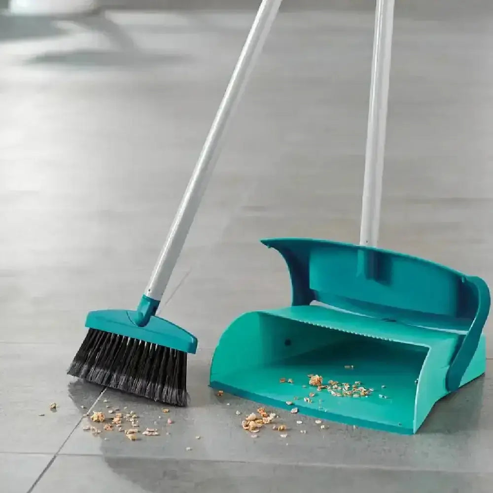 Teal broom and dustpan set on a tiled floor with scattered debris.