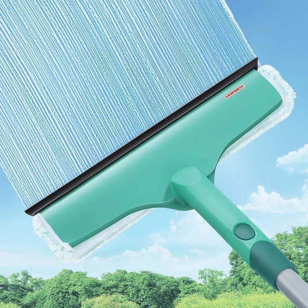 Green window cleaning tool with squeegee against a blue sky background