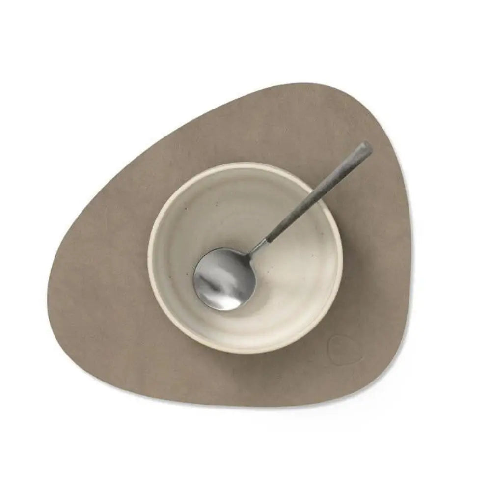 Serving dish with a spoon on placemat on a white background