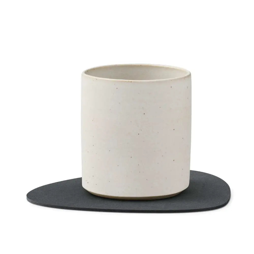 White ceramic mug on a black coaster with a white background