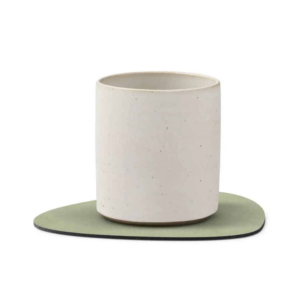White ceramic cup with a green coaster on a white background