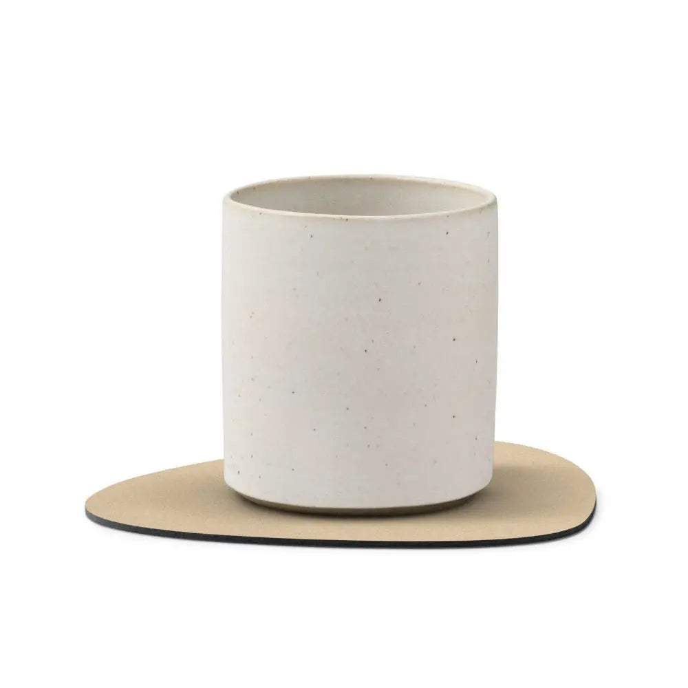 White ceramic cup with beige coaster on a white background