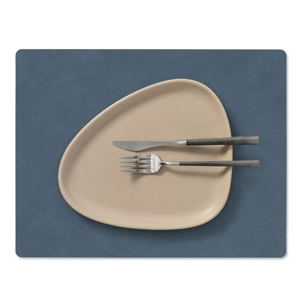 Beige plate with silverware on a blue placemat