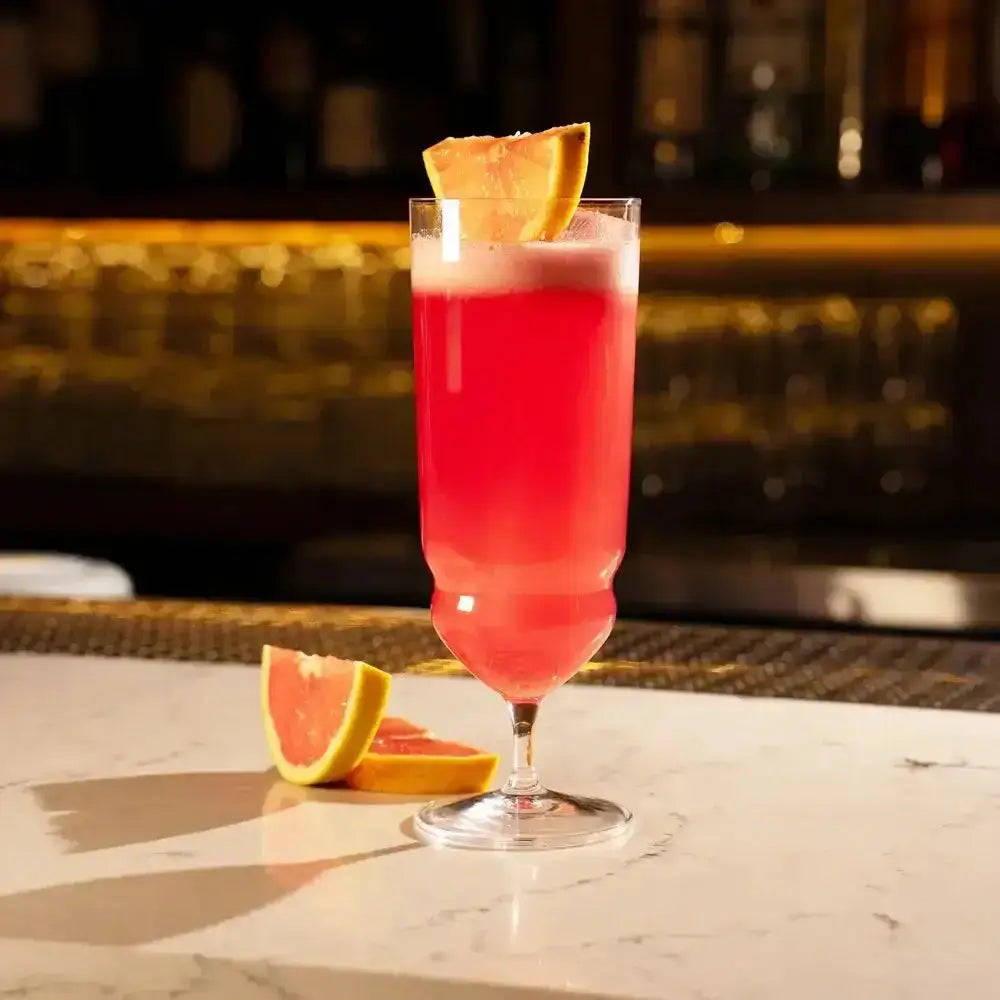 Pink cocktail with a slice of grapefruit on a bar counter