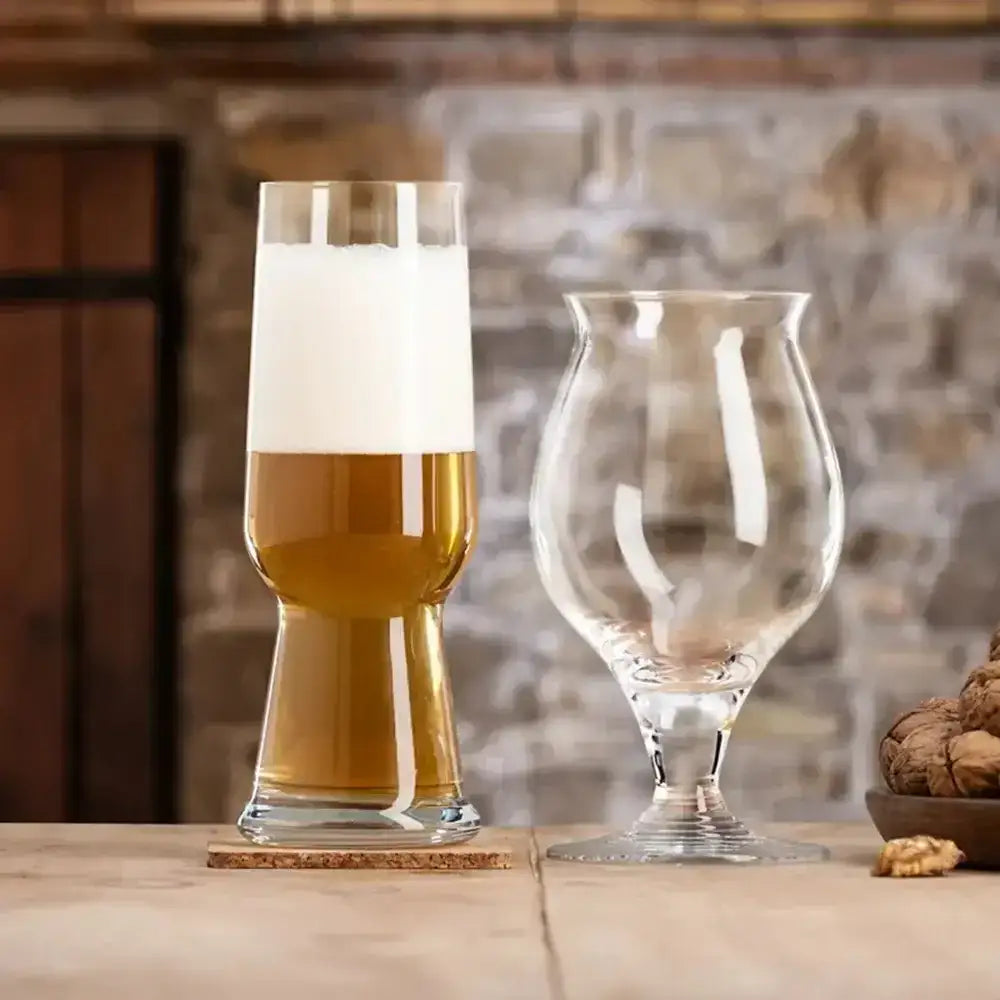 Two glasses of beer on a wooden surface with a stone wall background