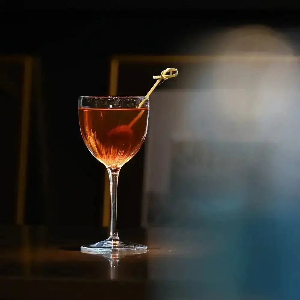 Cocktail in a glass with a gold stirrer on a dark background