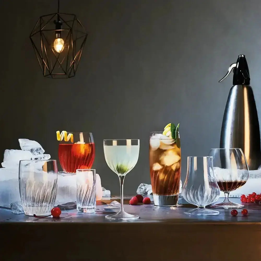 Cocktail setup with various glasses and a shaker on a dark background