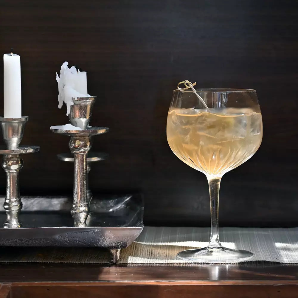 Cocktail in a glass with ice and a lemon twist on a dark background