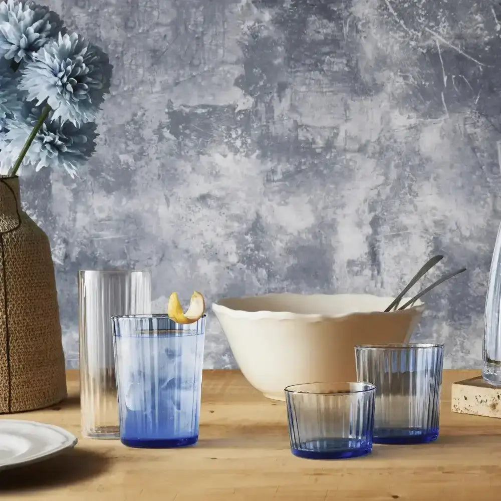 Set of blue glassware on a wooden table with a textured gray wall background