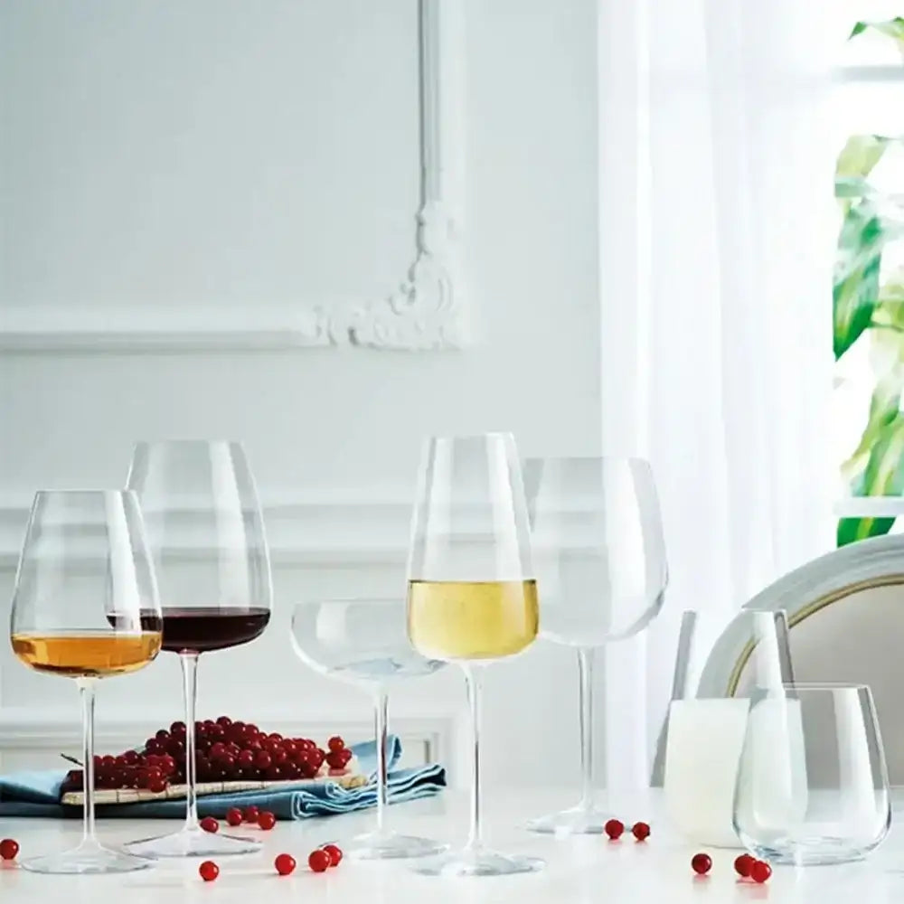 Set of wine glasses with different types of wine on a table with grapes and a white background.
