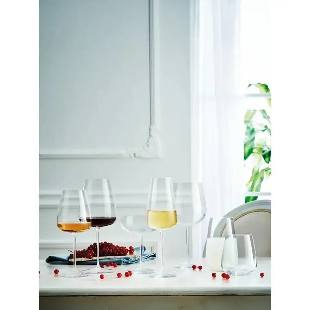 Wine glasses with different colored liquids on a white surface with a blurred background