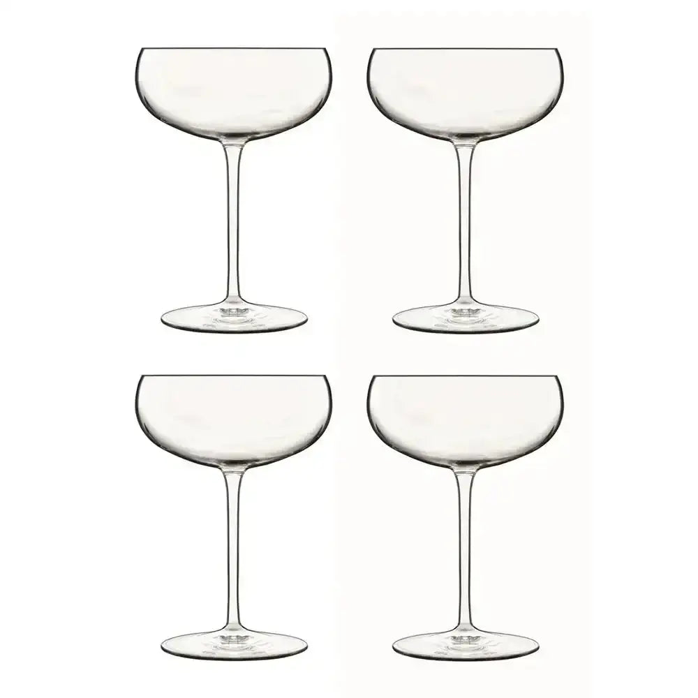 Four clear glass champagne coupes on a white background