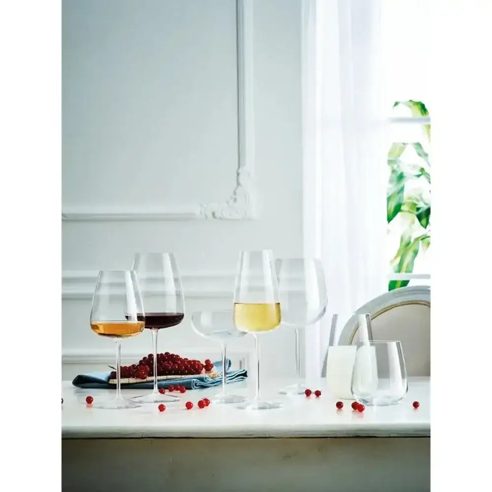 Set of wine glasses with different types of wine on a table with a white curtain in the background.