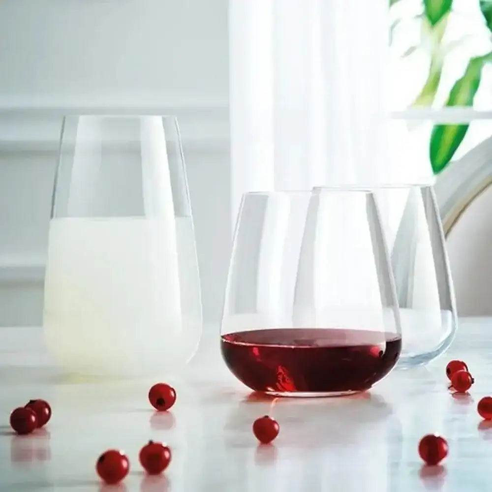 Two glasses, one with a red liquid and one with a white liquid, on a table with scattered red berries.