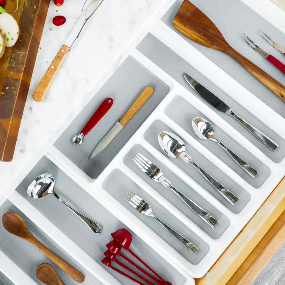 Silverware set with wooden utensils in a drawer organizer on a light background