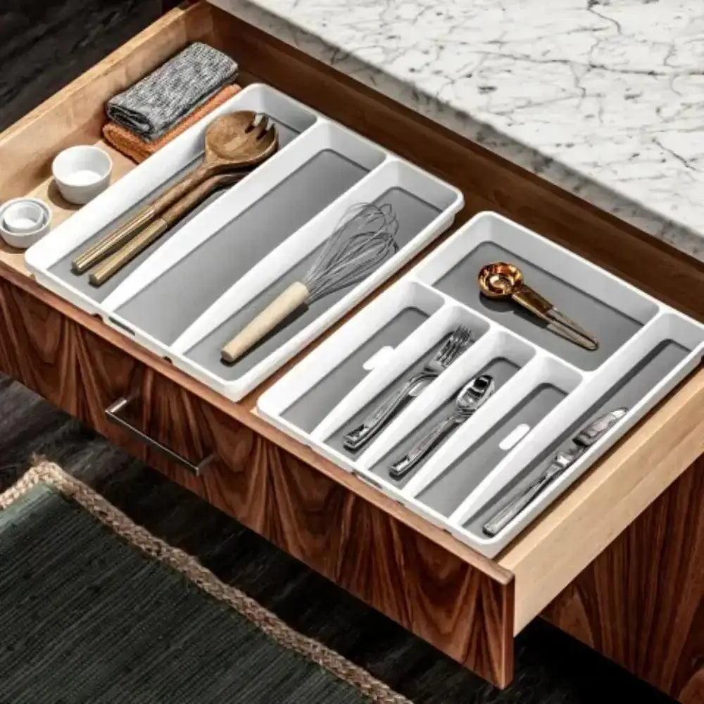 Kitchen drawer with organized cutlery and utensil holder on a wooden countertop.