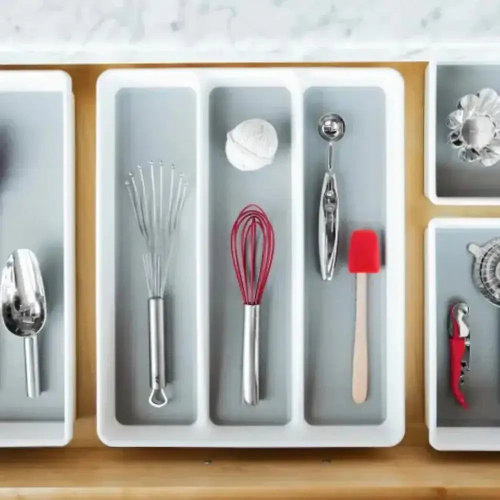 Kitchen utensils organized in a drawer organizer on a wooden surface.
