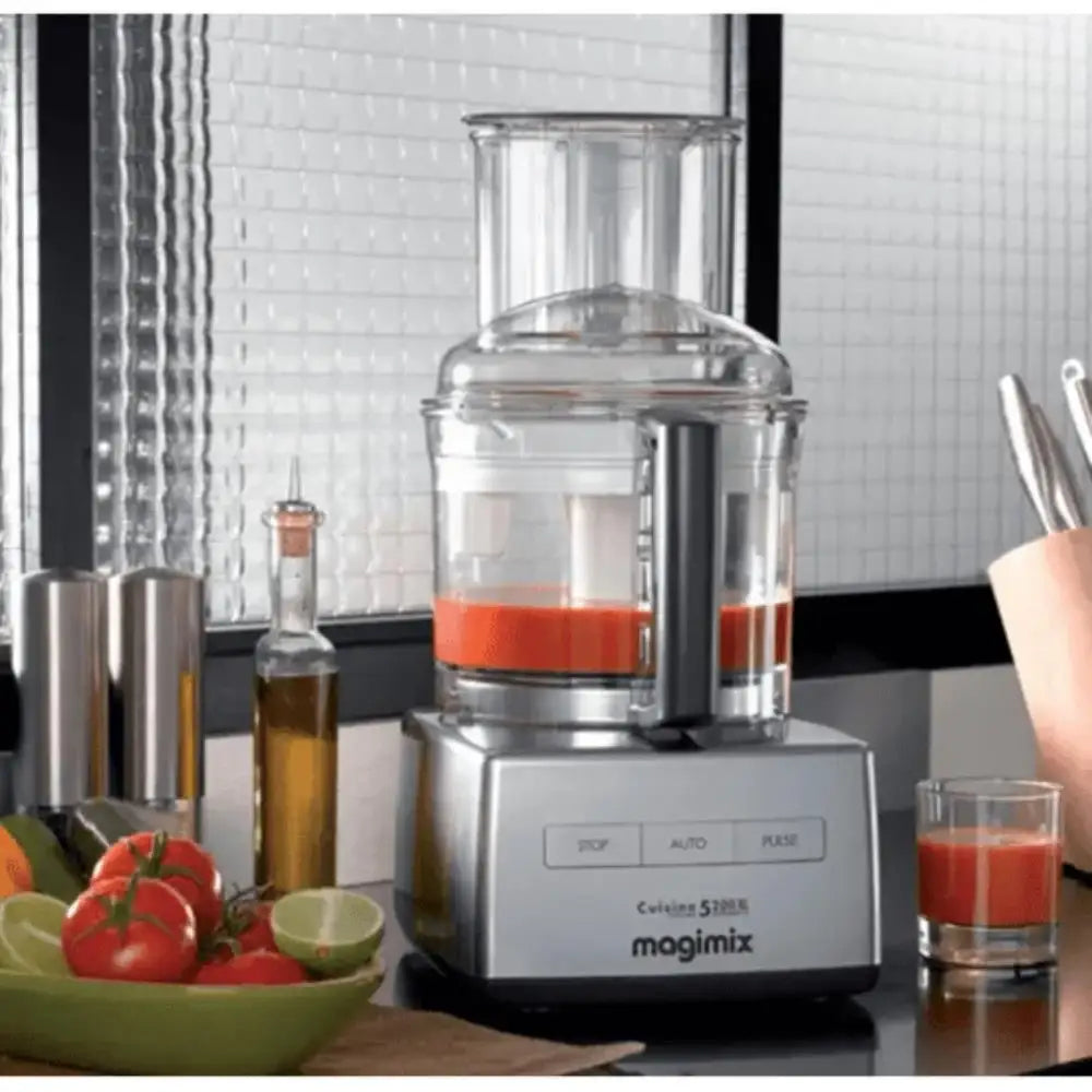 Magimix food processor with a glass container filled with red liquid on a kitchen counter.