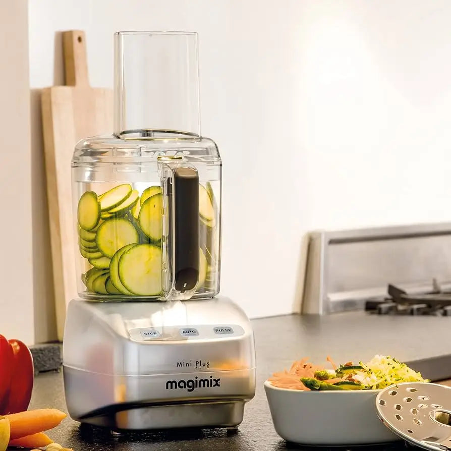 Magimix le mini plus food processor in chrome with clear plastic main bowl filled with sliced zucchini