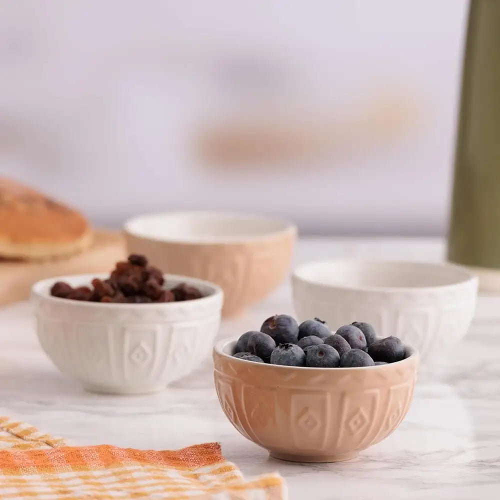 Two bowls with berries on a table with a blurred background