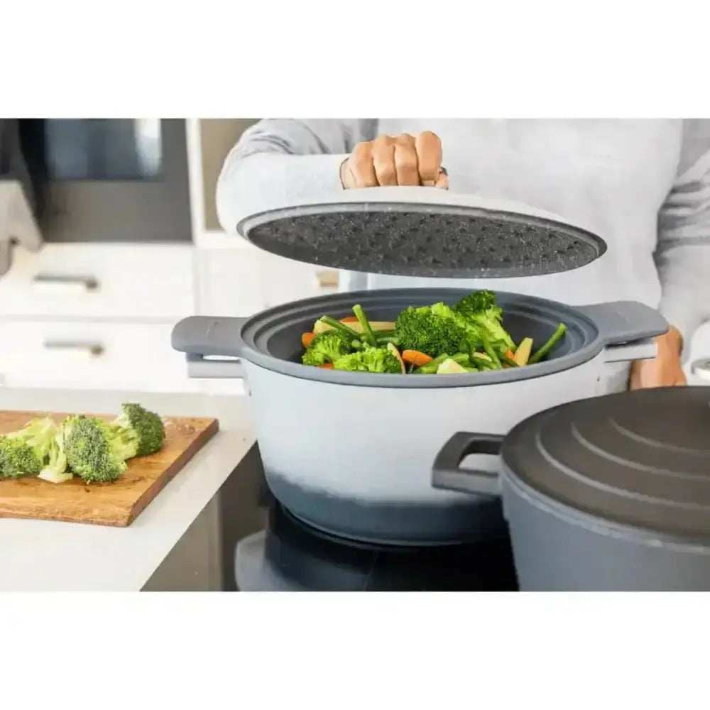 Person holding a gray pot with vegetables inside, kitchen setting