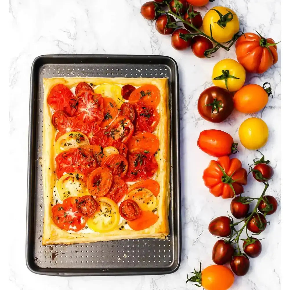 Tomato tart on a baking tray with a variety of tomatoes on the side