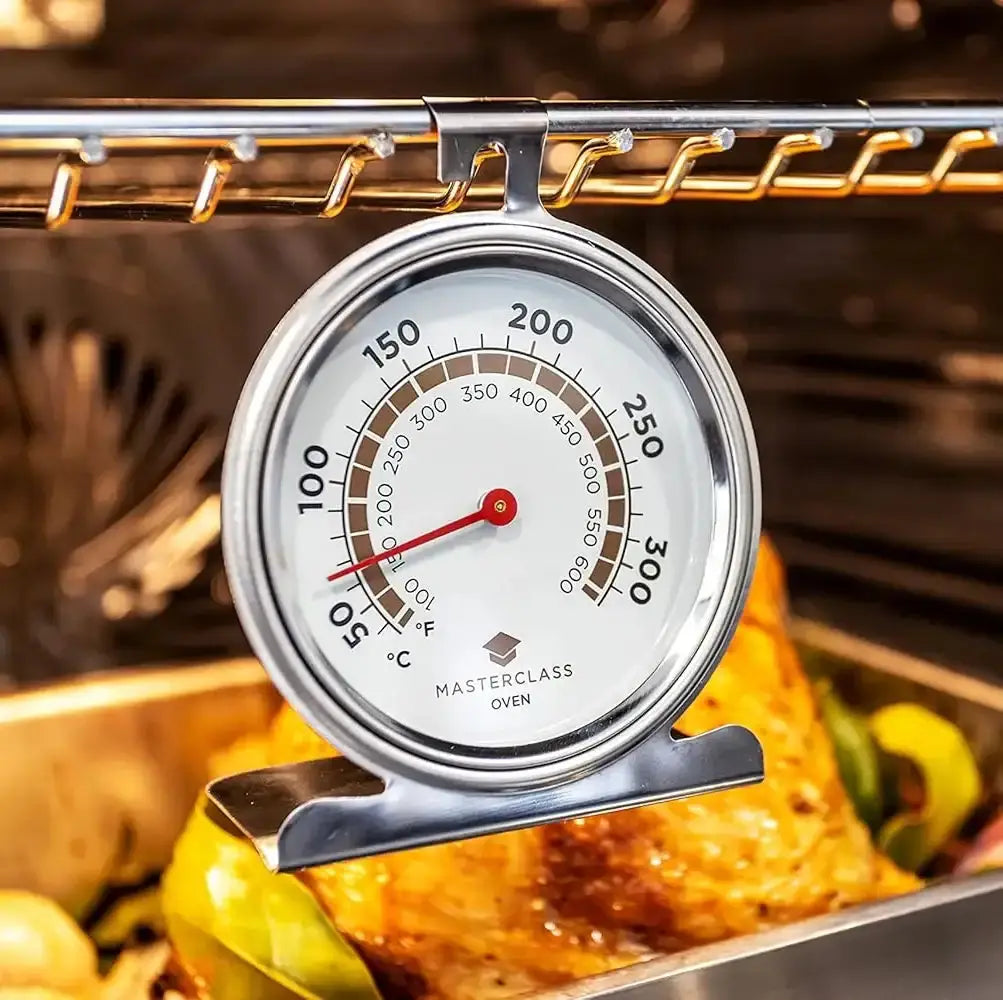 Oven thermometer in an open oven with food inside