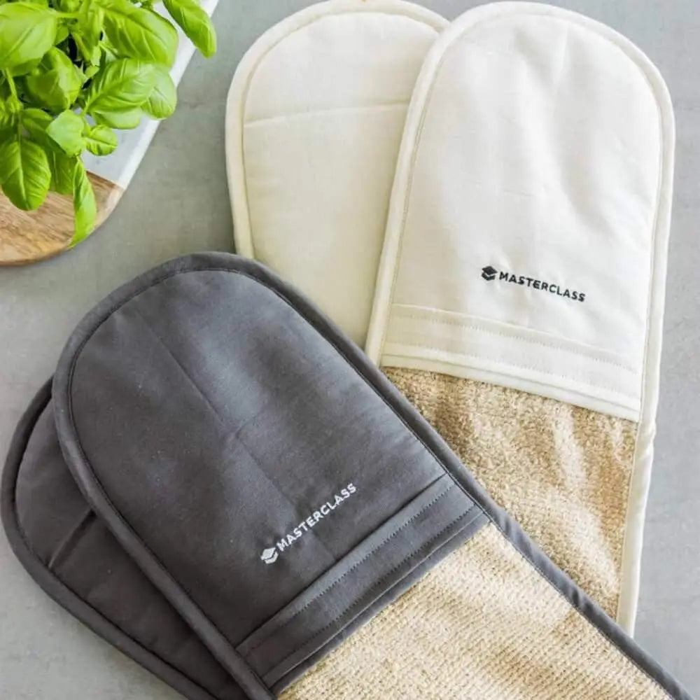 Gray and beige oven mitts with 'Masterclass' branding on a gray surface.