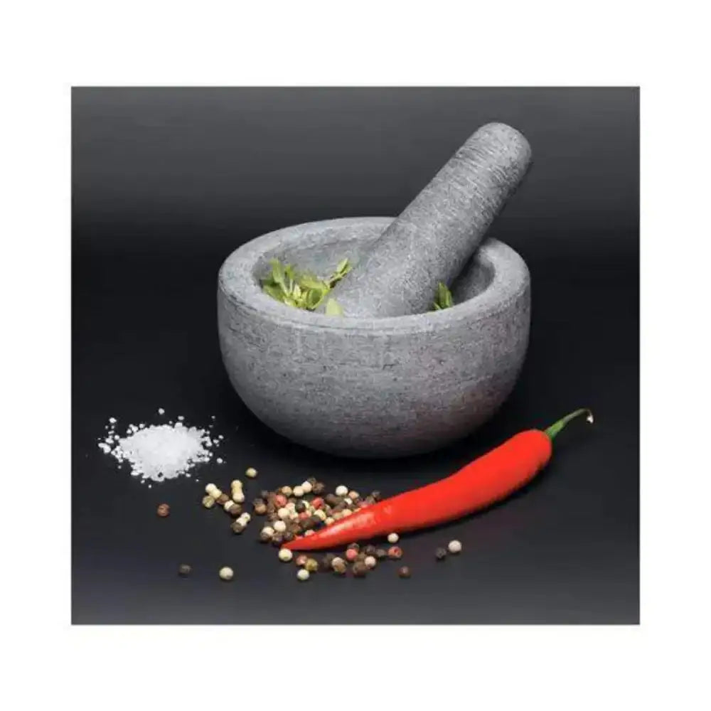 Gray mortar and pestle with herbs, red chili pepper, and spices on a black background