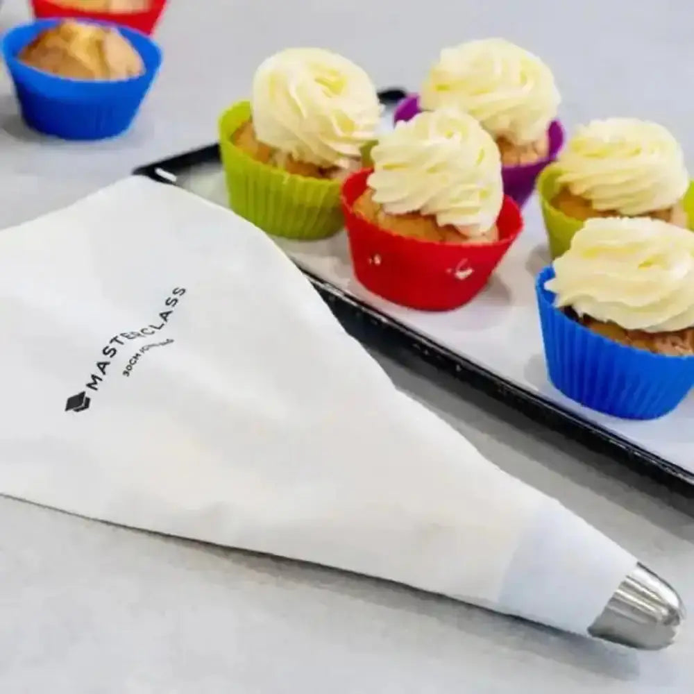 Cupcakes with white frosting in colorful silicone molds on a tray, with a piping bag and 'Mast Class' branding.
